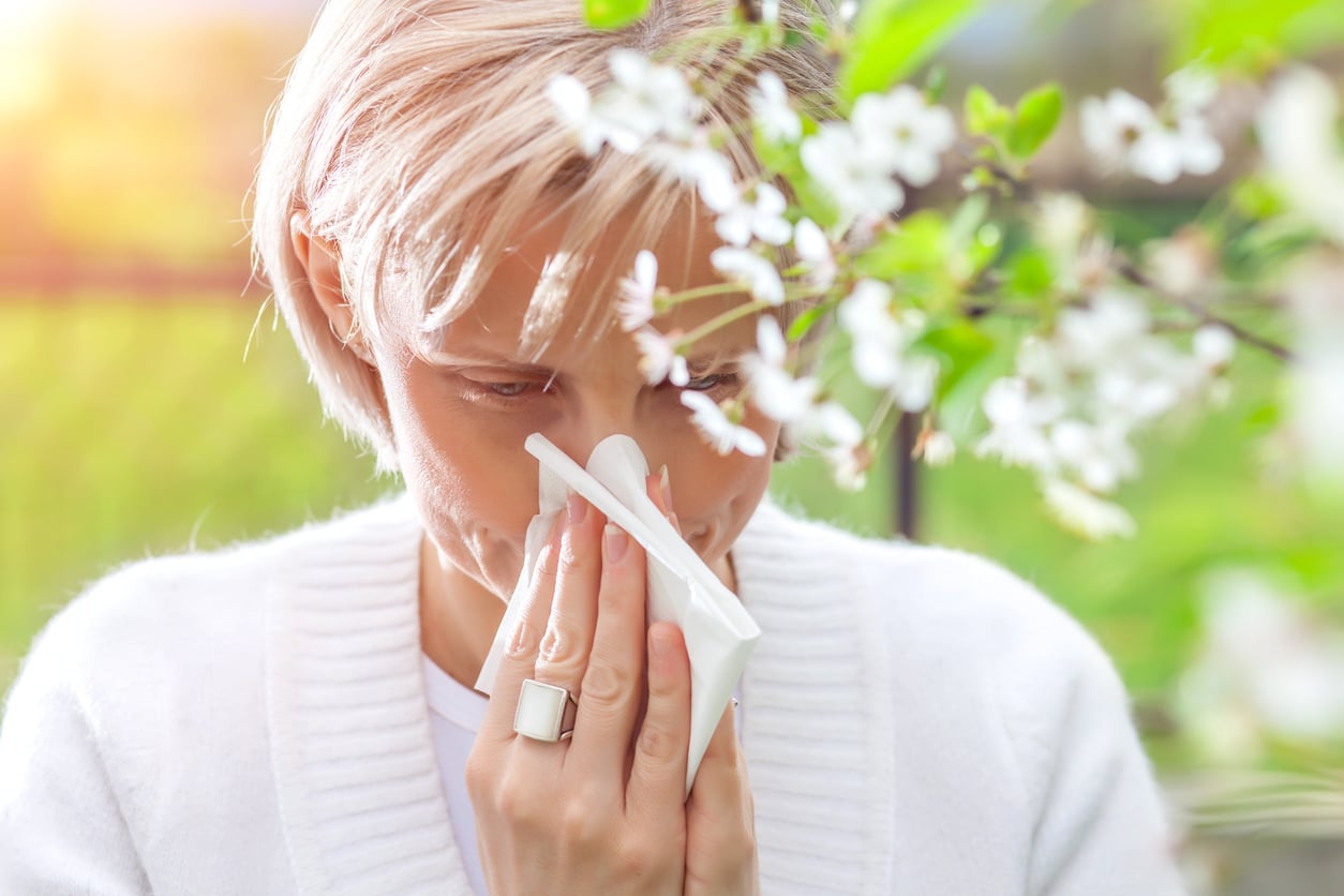 Woman blowing her nose outdoors and looking for hay fever relief